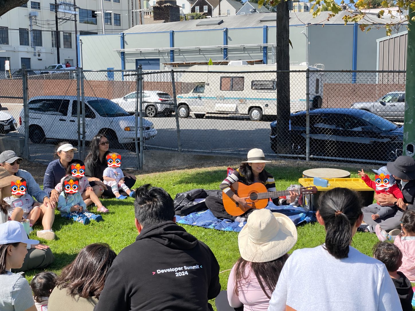 A song leader playing guitar for kids and parents seated on the grass